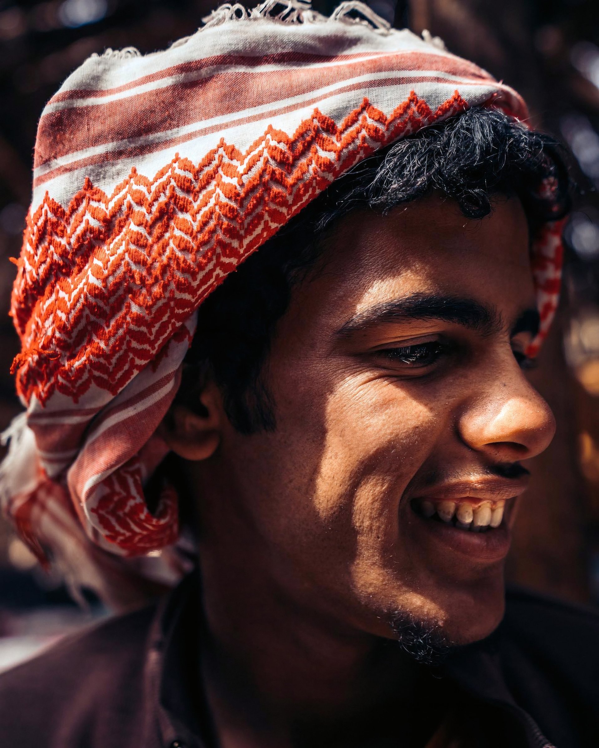 Smiling young man wearing a red and white head covering.