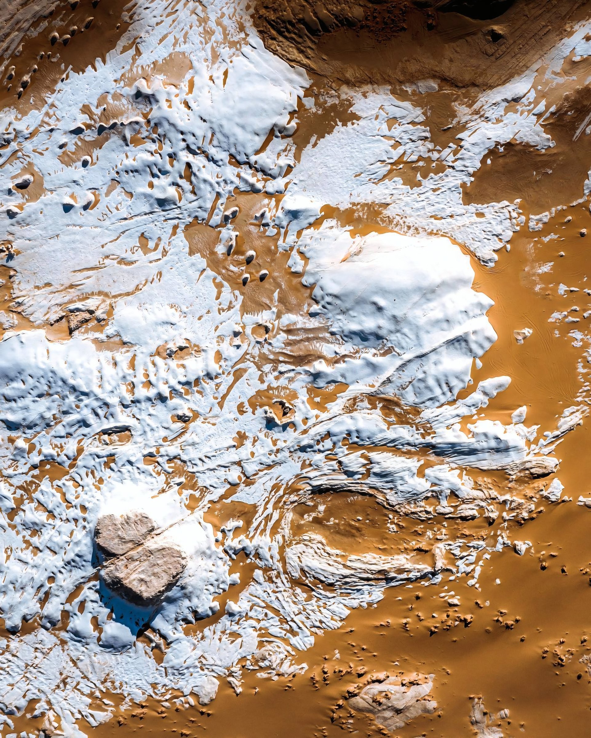 Aerial view of textured brown terrain and white ice.